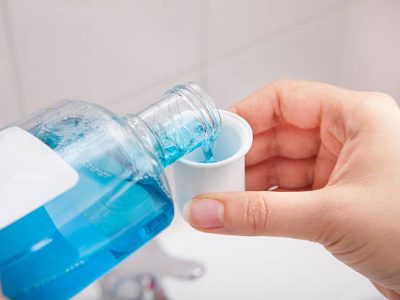 Close-up Of Person's Hand Pouring Liquid In Container