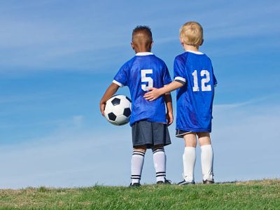A rear view photo of two kids on a youth recreation league soccer team. Diverse little boys